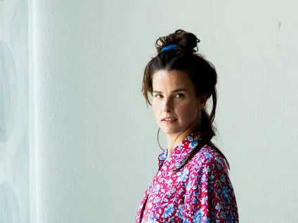 Frida Österberg iklädd blommig jumpsuite med uppsatt hår mot grå bakgrund